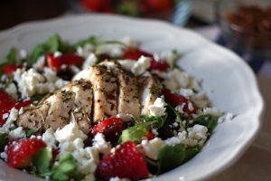 Adding feta to the Arugula Salad with Baked Chicken, Strawberries, and Pecans